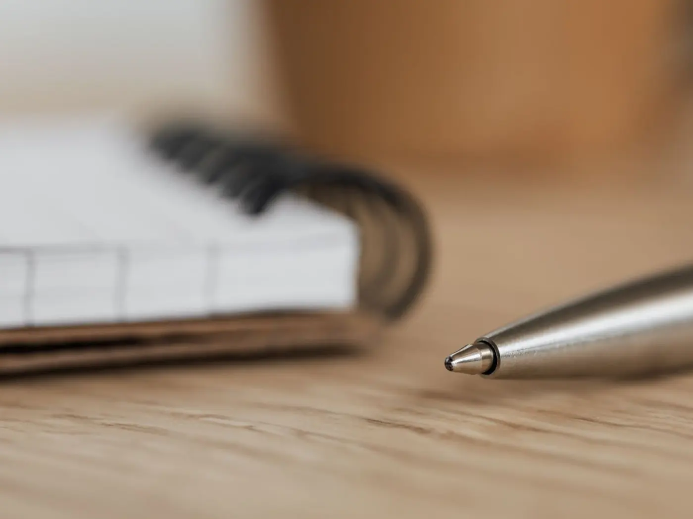 Cuaderno de espiral y un bolígrafo sobre una mesa de madera clara